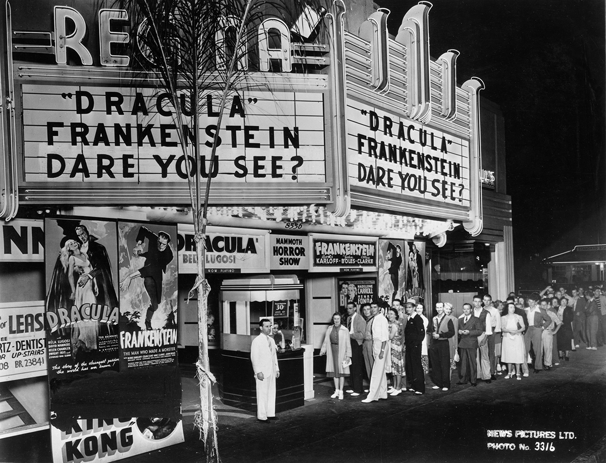 Exterior image of Regna theatre, black and white image, people standing at the box office, 